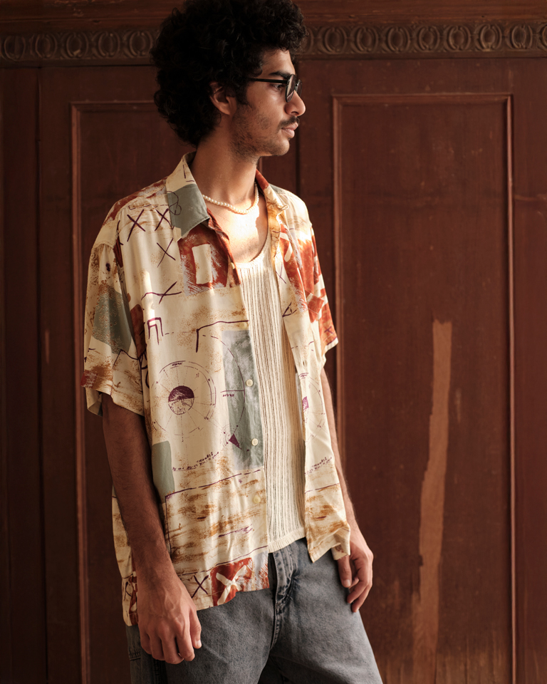 Abstract print Cuban collar shirt from Now + Thenn, featuring vintage-style patterns in earthy tones, worn casually with denim.