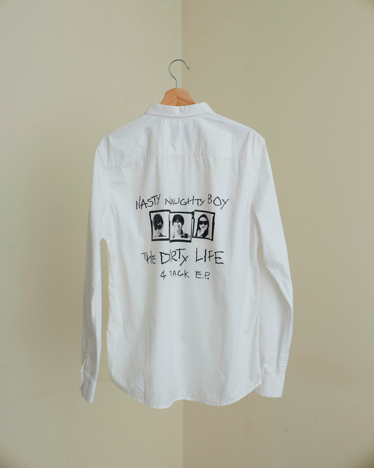 Unisex white graphic button-down shirt by Now + Thenn with “Nasty Naughty Boy” and “The Dirty Life” printed text and photo graphics.