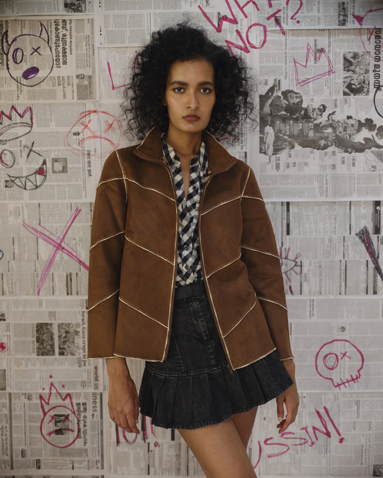 Model wearing a vintage- brown suede panel jacket with contrast white stitching and shearling lining from Now + Thenn.