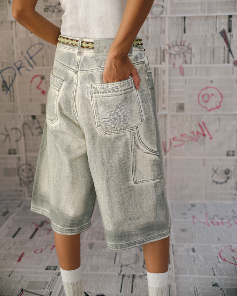 Unisex light gray washed denim carpenter shorts with knee-length wide legs, slanted pockets, and dragon embroidery on the back pocket