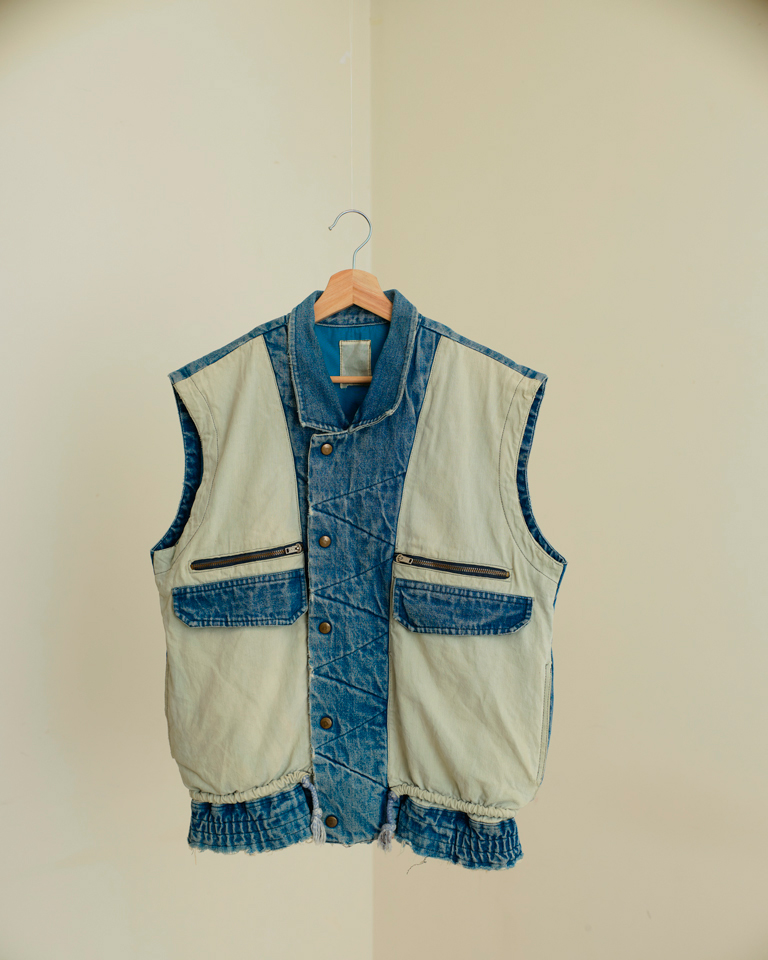 Upcycled vintage denim utility vest by Now + Thenn featuring contrast patchwork panels, zip pockets, snap buttons and elastic hem in a unisex sleeveless jacket design.