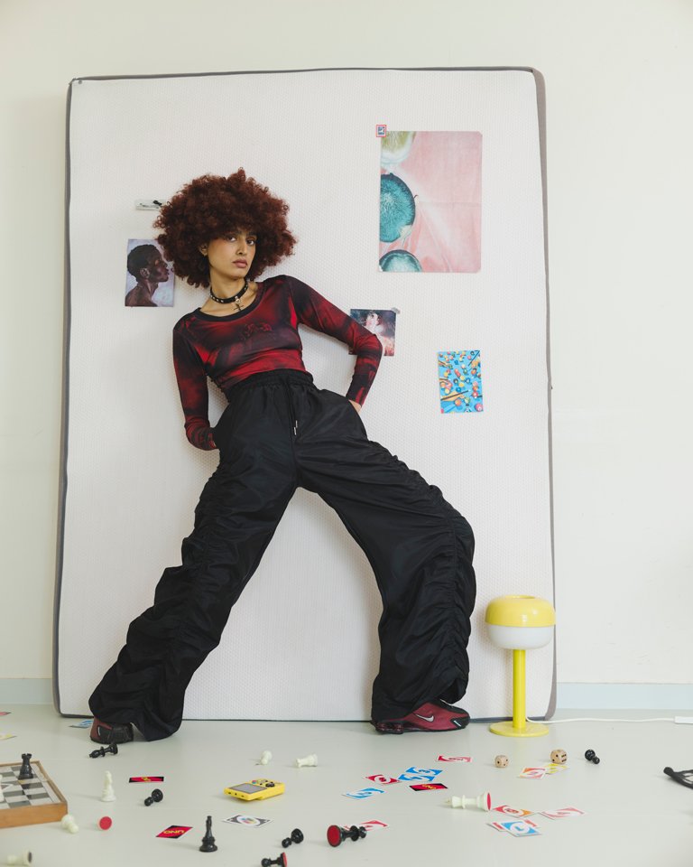Model wearing red body print long sleeve top with high-waisted black pants, fitted silhouette.