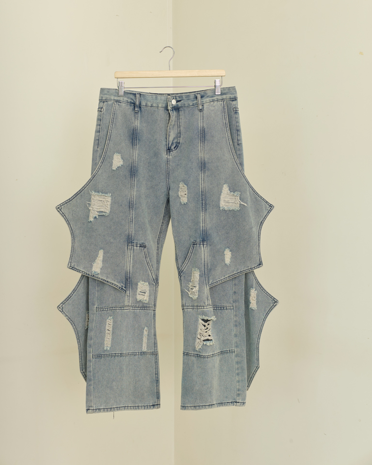 Light wash wing panel distressed denim jeans with sculptural side extensions and wide-leg fit by Now + Thenn.