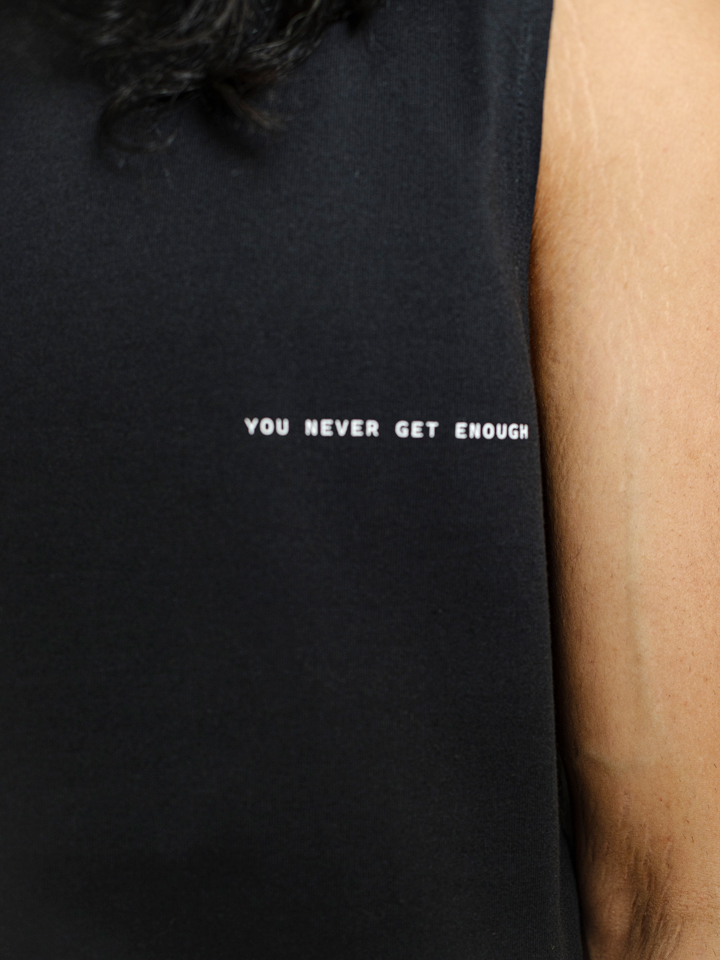 Black sleeveless tank top with “Sex Is Like Drugs” minimal text print and relaxed silhouette by Now + Thenn.