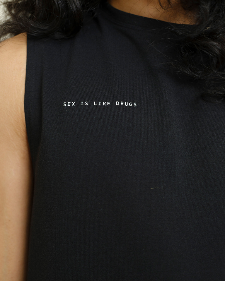 Black sleeveless tank top with “Sex Is Like Drugs” minimal text print and relaxed silhouette by Now + Thenn.