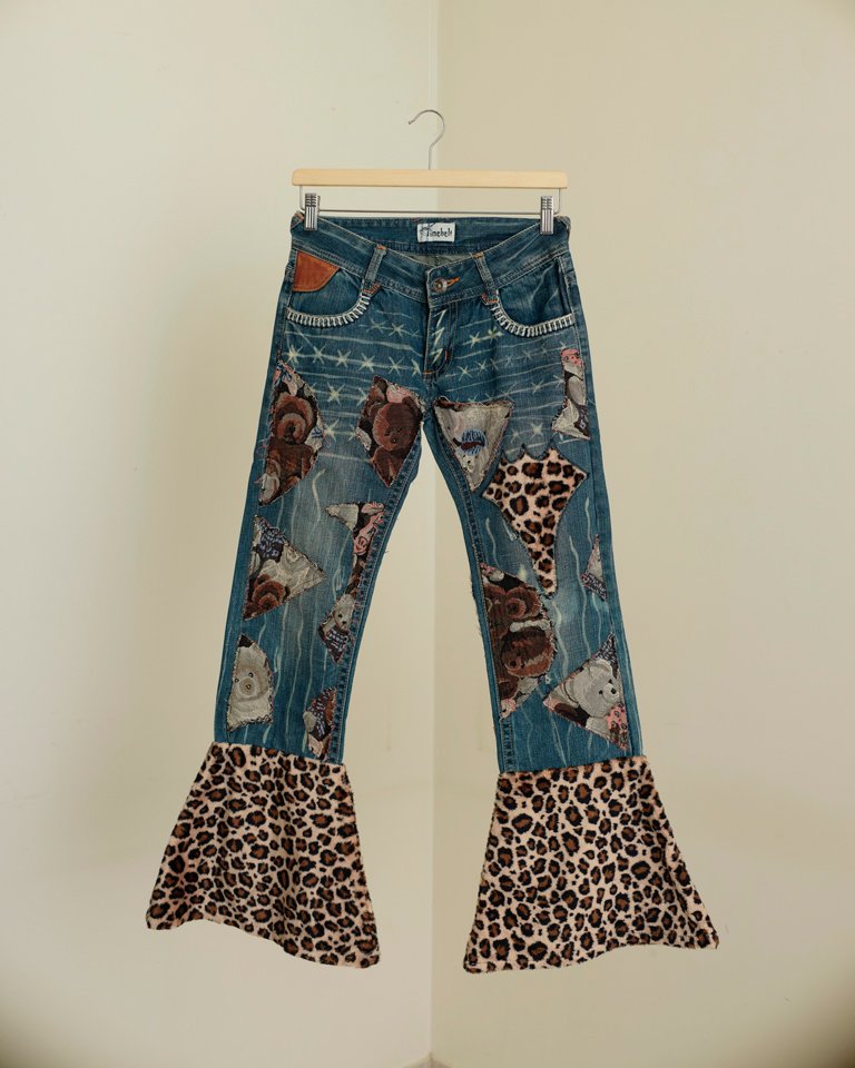 Upcycled patchwork flare jeans featuring teddy bear appliqués, leopard-print panels, distressed denim details and oversized bell-bottom hems by Now + Thenn.