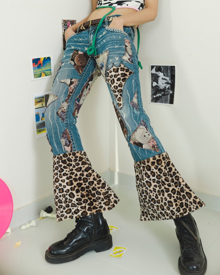 Upcycled patchwork flare jeans featuring teddy bear appliqués, leopard-print panels, distressed denim details and oversized bell-bottom hems by Now + Thenn.