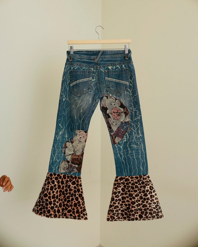 Upcycled patchwork flare jeans featuring teddy bear appliqués, leopard-print panels, distressed denim details and oversized bell-bottom hems by Now + Thenn.