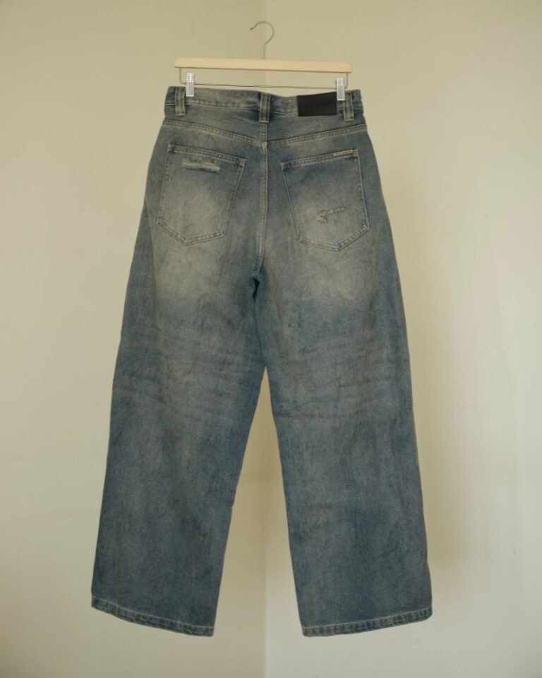 Washed blue baggy denim jeans with curved front panel detailing and distressed accents