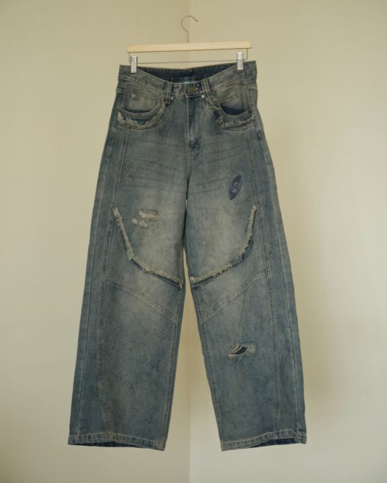 Washed blue baggy denim jeans with curved front panel detailing and distressed accents