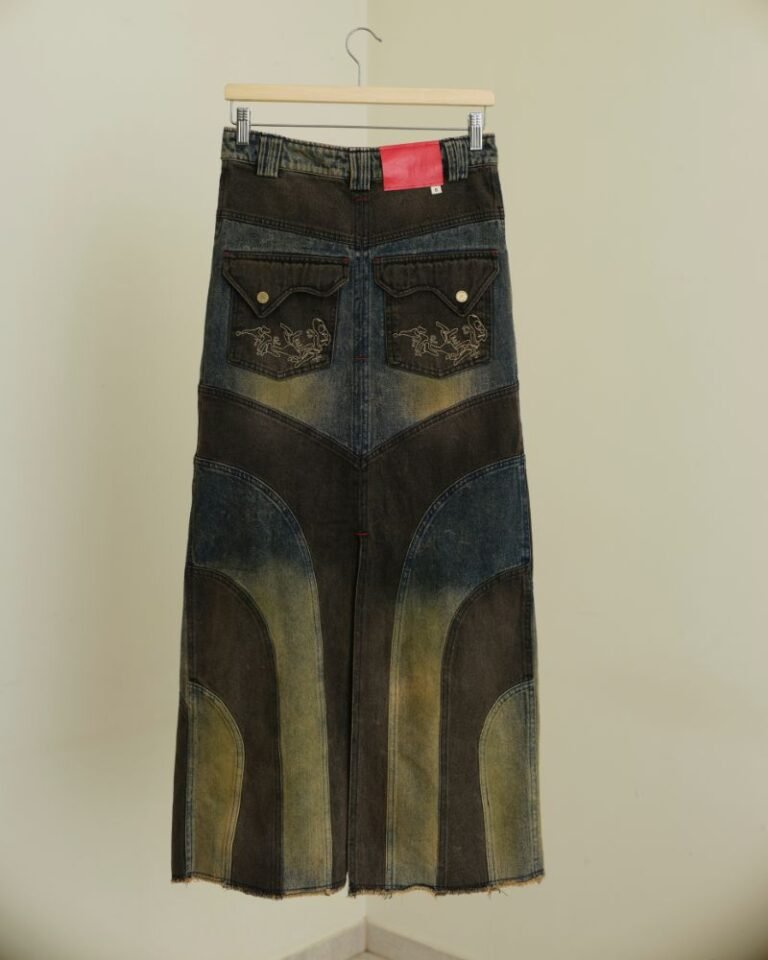 Upcycled blue and dark denim skirt with curved panels, metal grommets and raw hem